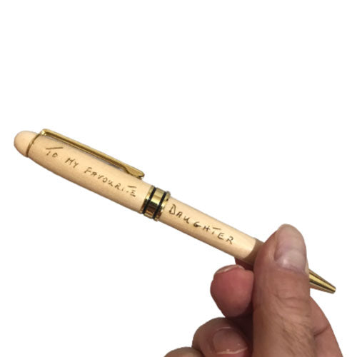 a hand holding a wooden personalised pen engraved with a handwritten message